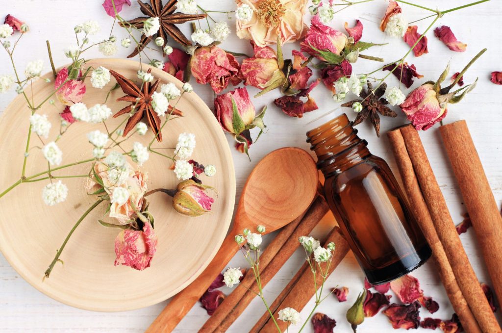 Dried out flowers and spices, including roses and connamon, on a light background, with a plate and wooden spoon explaining what is an accord