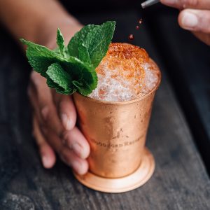 Hand squeezing lime into a rum cocktail