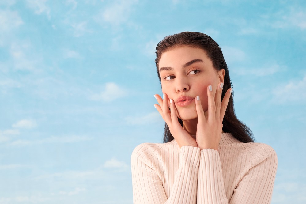 young female model pouting with hands up against cheeks