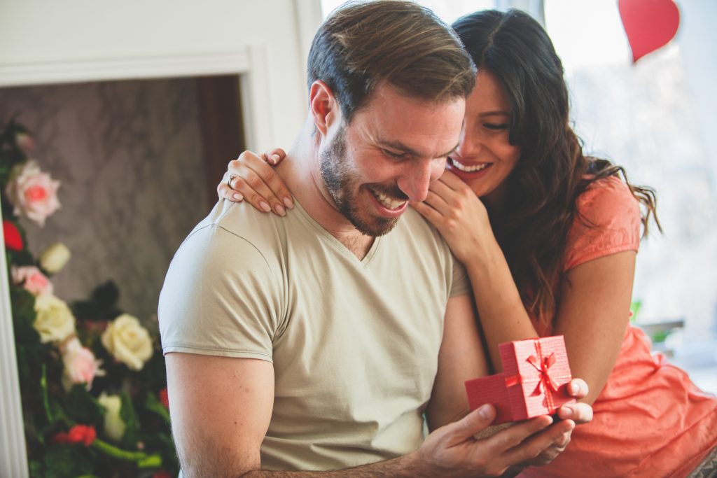 Woman giving man a small gift, both smiling