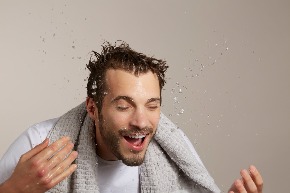 Male model splashing face with water