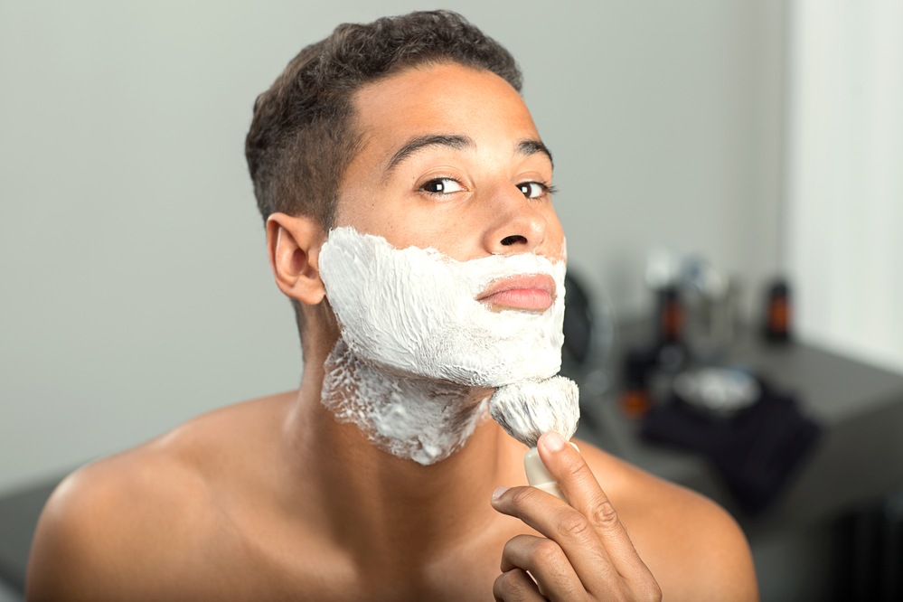 Male applying beard shaving cream with a brush