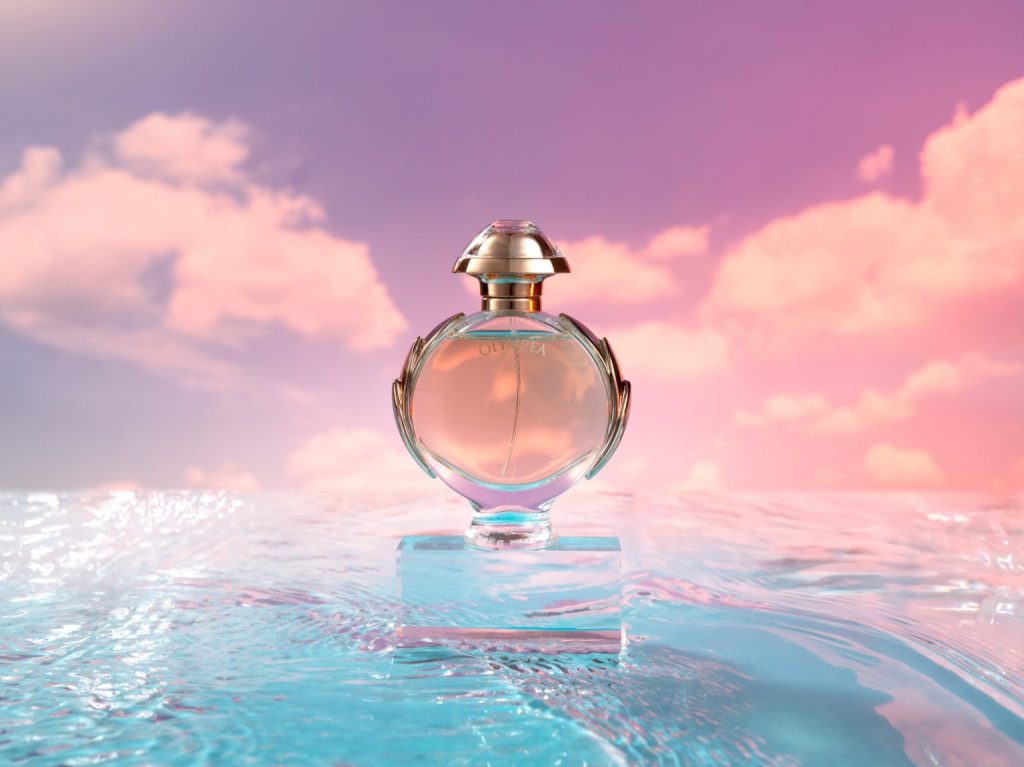 Olympea by Paco Rabanne bottle on glass box on water with sunset background