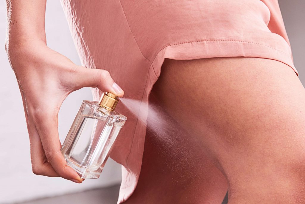 Lady spraying perfume behind her knee for pulse points on the body article