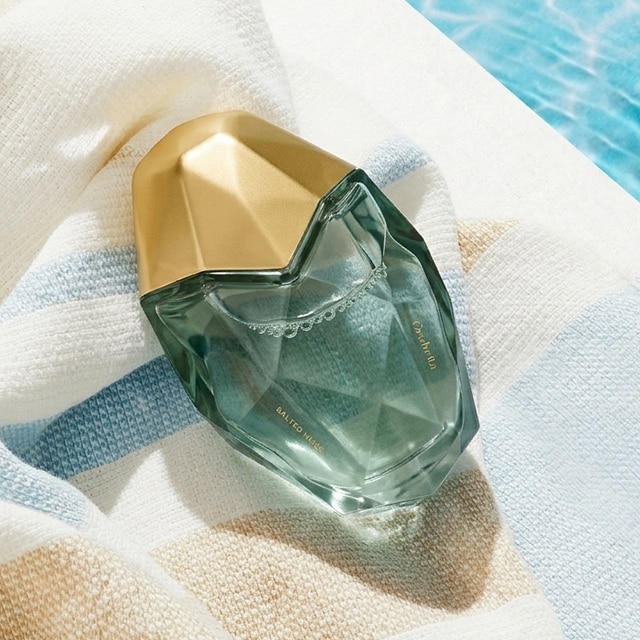Image of perfume on beach towel