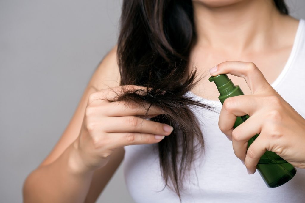 Brunette female applying oil to the ends of her hair