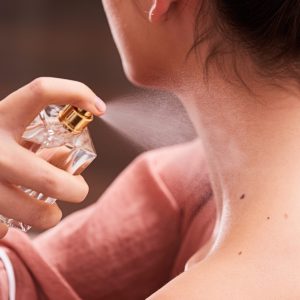 Close up of female spraying neck with perfume