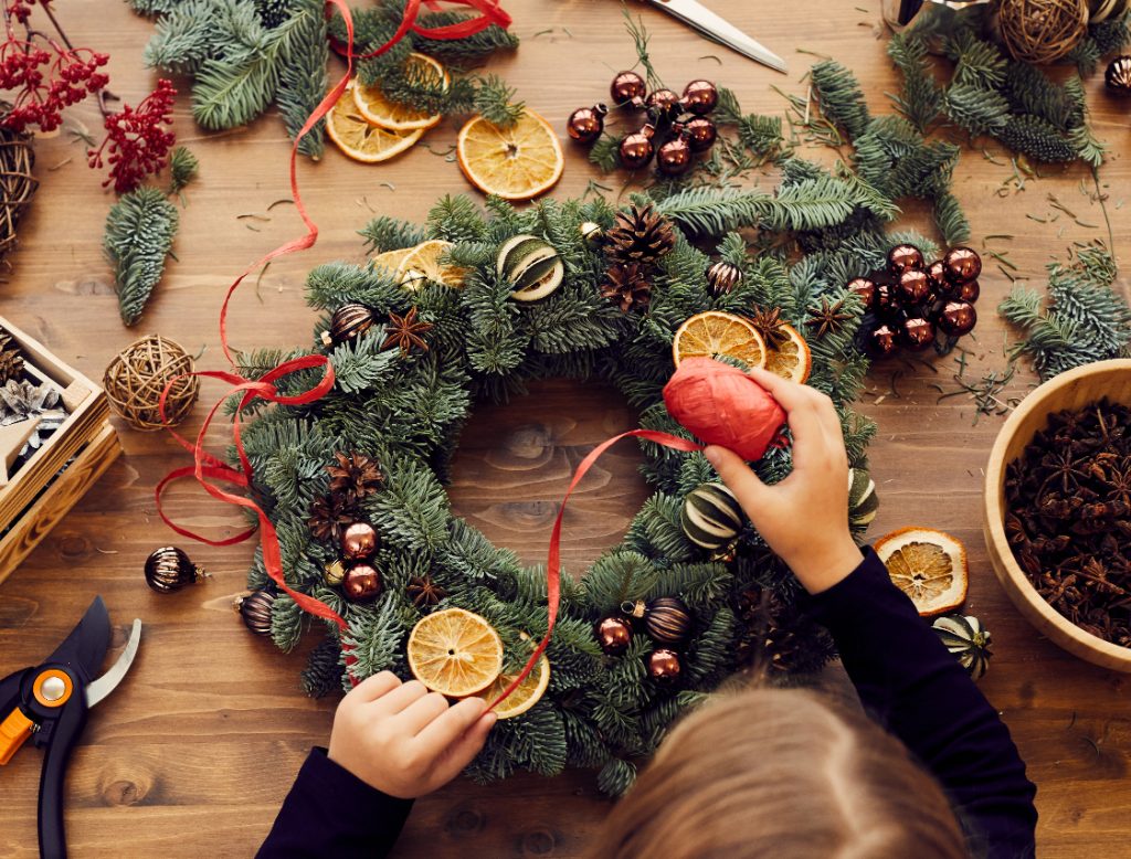 Homemade Christmas wreath with red ribbon being attached