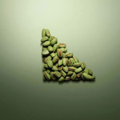 Image of pistachios arranged in the shape of a triangle on a green background