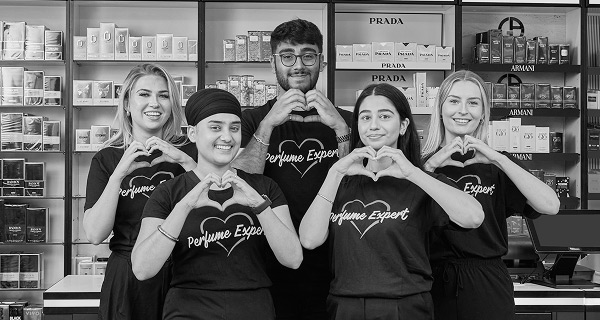 A male employee of the perfumeshop standing with two female employees willing to offer helpful services