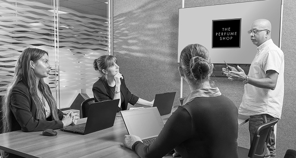 A male employee of the perfumeshop standing with two female employees willing to offer helpful services