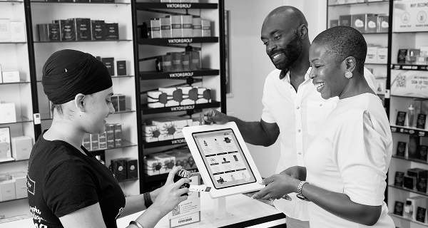 Male model holding a cell phone looking at the perfume shops app.
