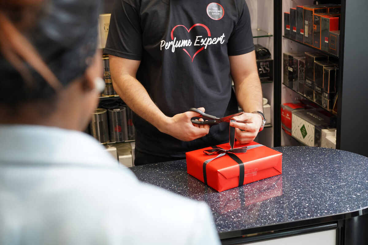 A member of staff gift wrapping perfume