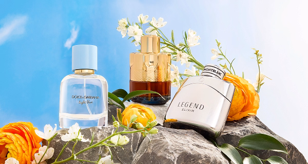 Perfume bottles placed on rocks surrounded with flowers