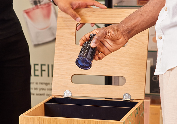 Throwing a perfume bottle into bottle recycling bin 