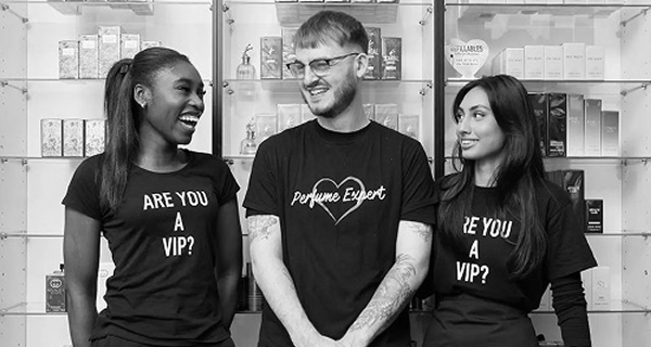 A male employee of the perfumeshop standing with two female employees willing to offer helpful services