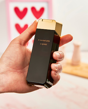 A hand holding a perfume bottle with engraving on it