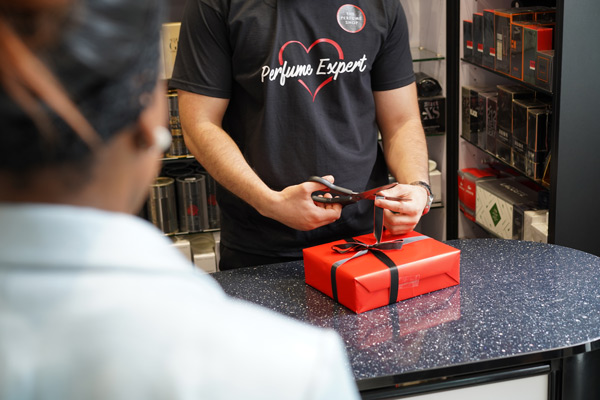A person wrapping a gift of perfume