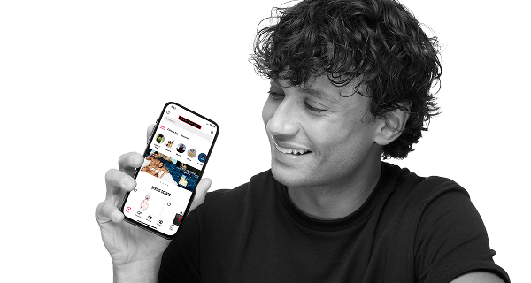 Male model holding a cell phone looking at the perfume shops app.