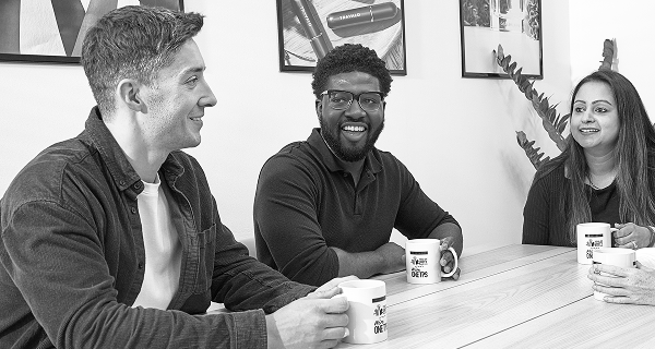 People sitting around a board room table in conversation with coffee