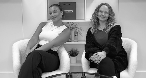 Two females sitting on comfortable chairs posing for a photograph