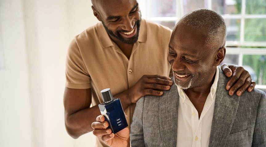 A father and son smiling while holding an engraved perfume bottle