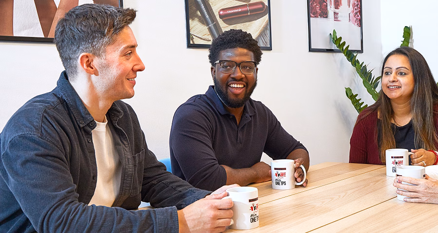 People sitting around a board room table in conversation with coffee