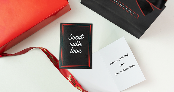 A greeting card on a table surrounded by a gift bag and ribbon