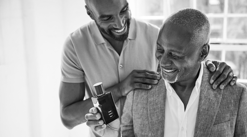 A father and son smiling while holding an engraved perfume bottle