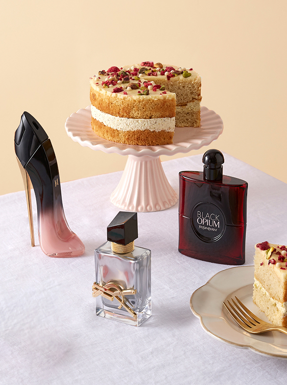 3 bottles of perfume on a table, surrounded by cake
