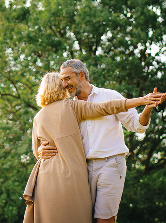 An elderly man and woman dancing in a park