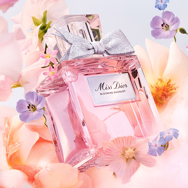 A bottle of Miss Dior Blooming Bouquet floating with its ingredients