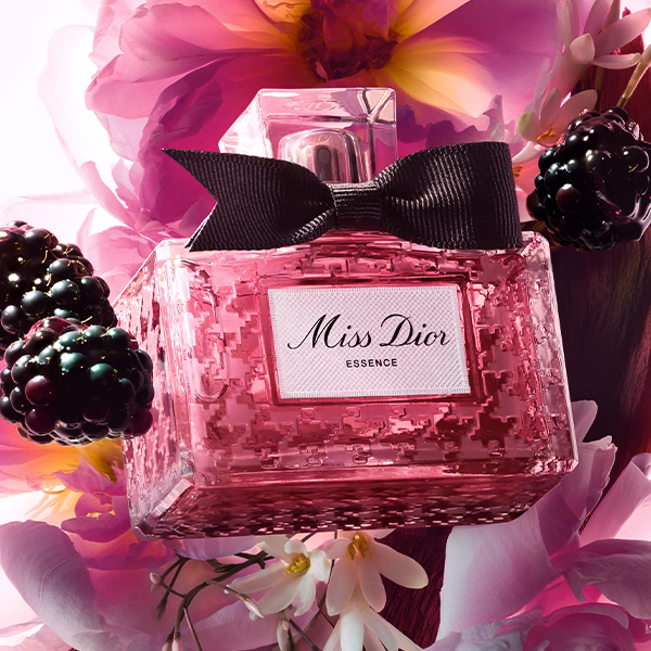 A bottle of Miss Dior Essence floating with its ingredients