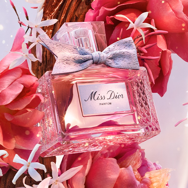 A bottle of Miss Dior Parfum floating with its ingredients
