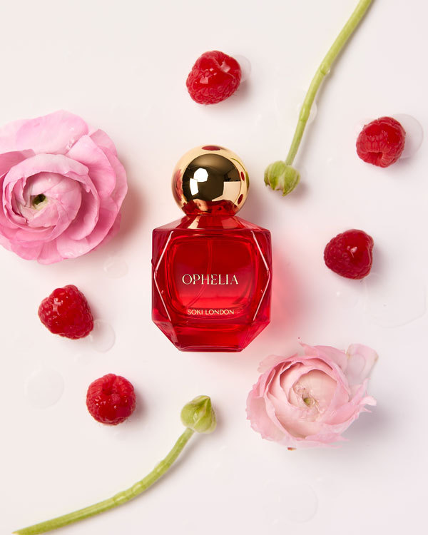 SOKI London Ophelia perfume bottle with gold cap, surrounded by pink florals and raspberries on a clean white background